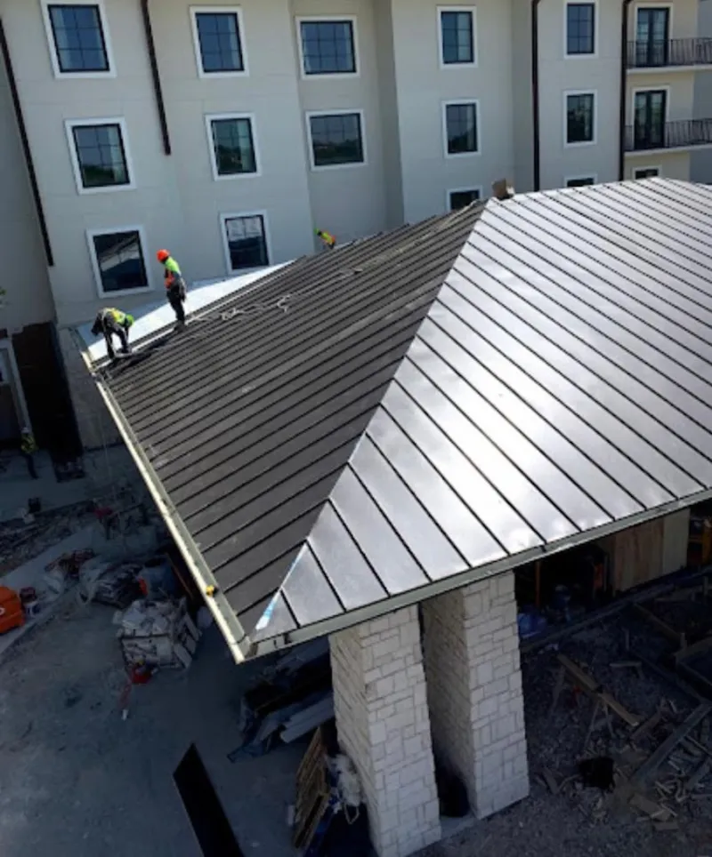 Crew installing standing seam metal roof panels on a commercial project in Gladstone